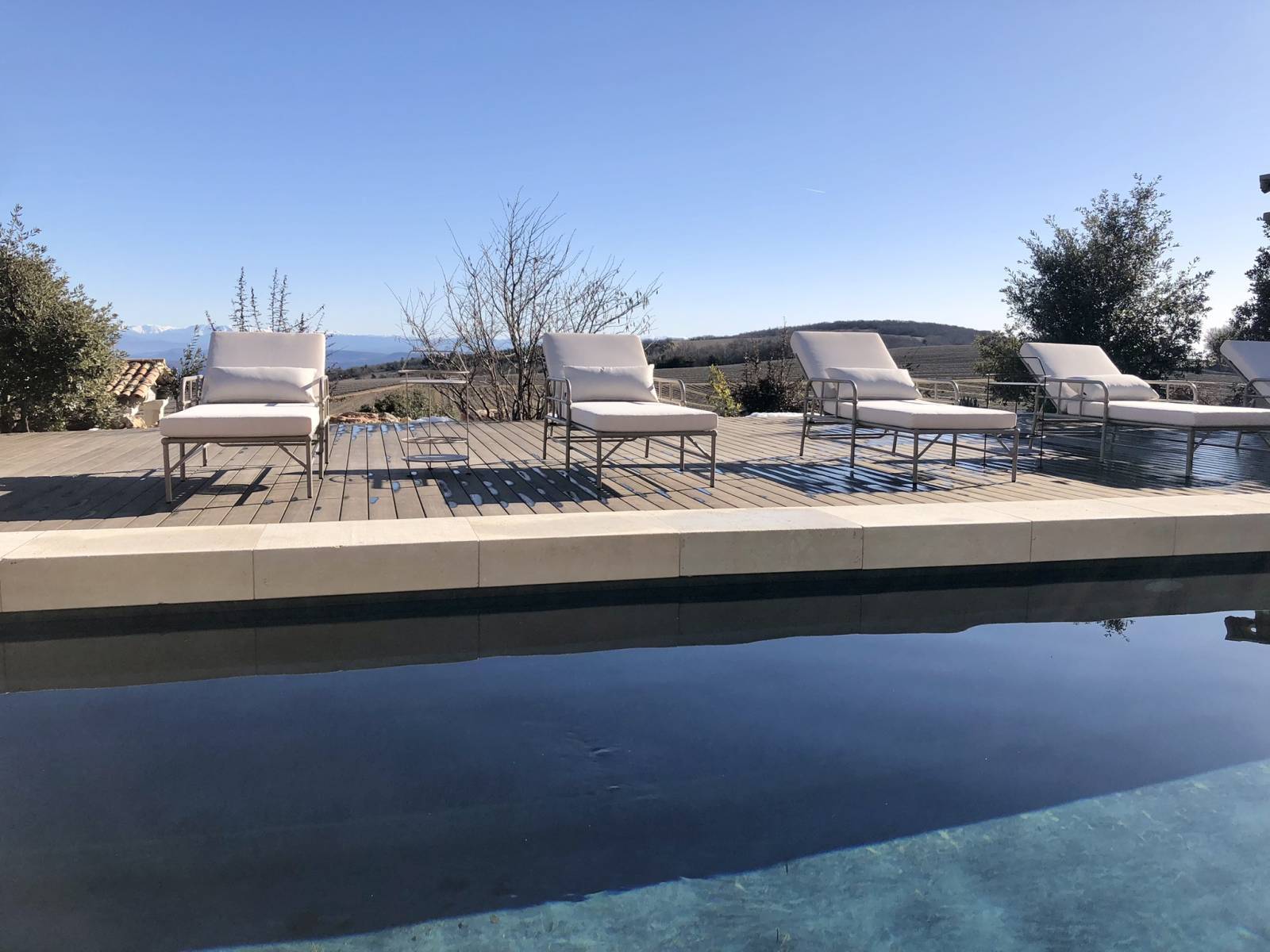 La piscine chauffée et sa plage en teck avec des chaises longues au Domaine Château du Bois
