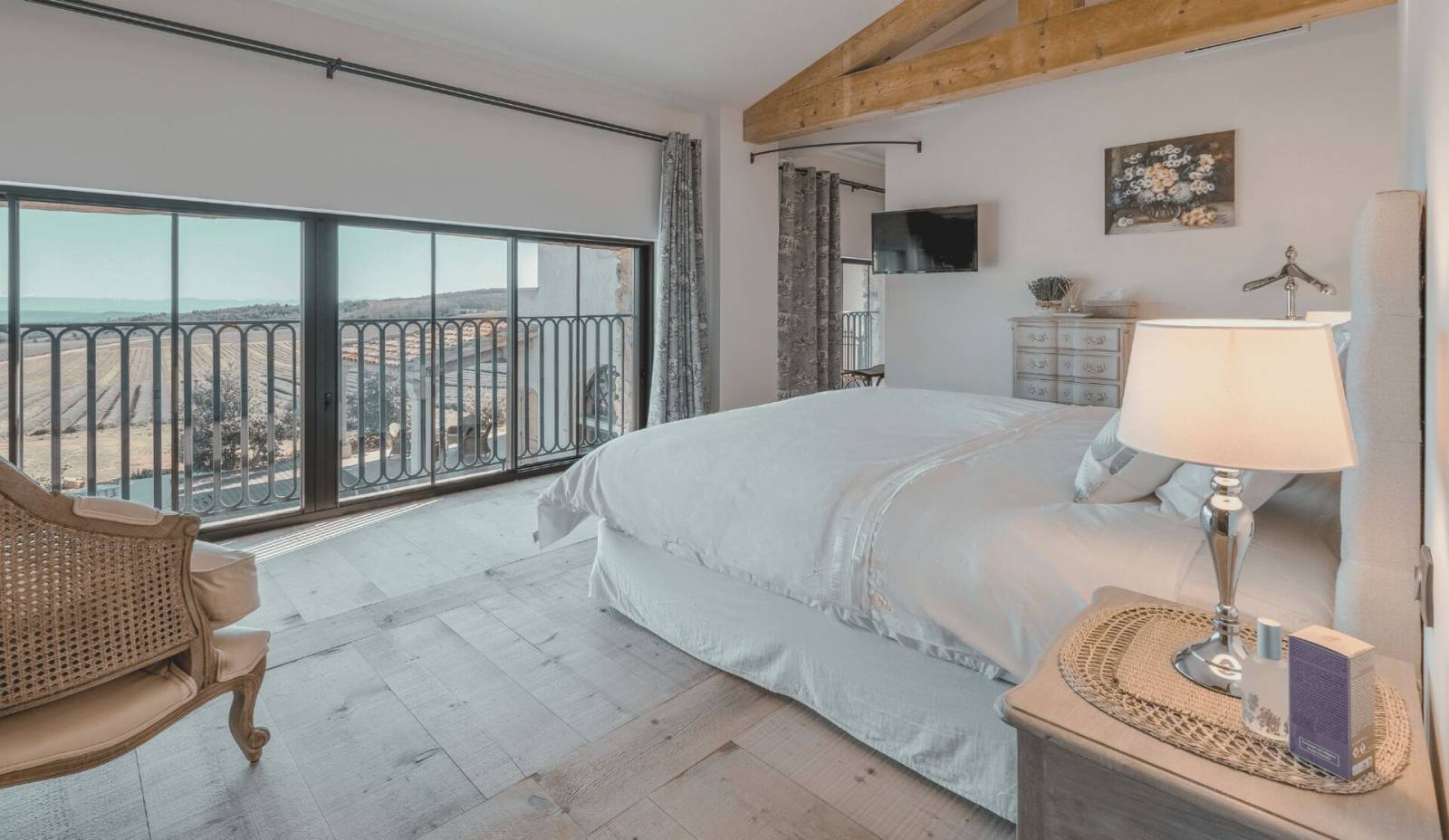 Lit king-size avec vue sur les champs de lavande depuis la Chambre Deluxe Marius au Domaine Château du Bois