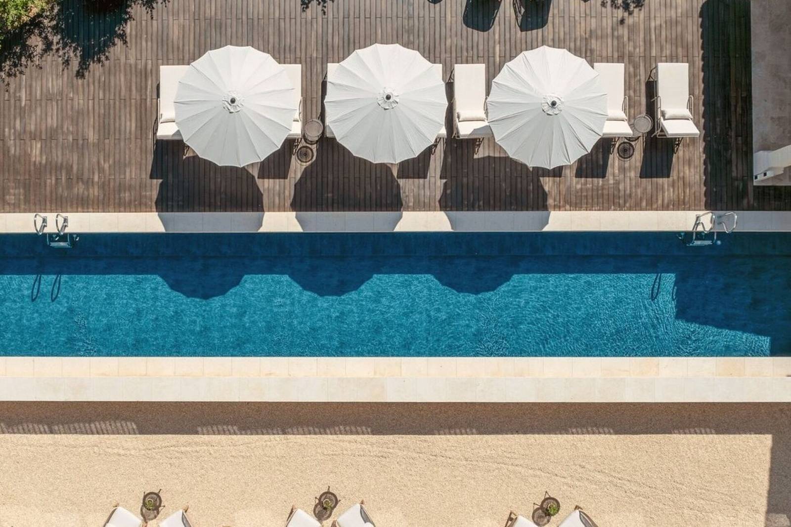 Vue aérienne de la piscine chauffée et sa plage en teck au Domaine Château du Bois