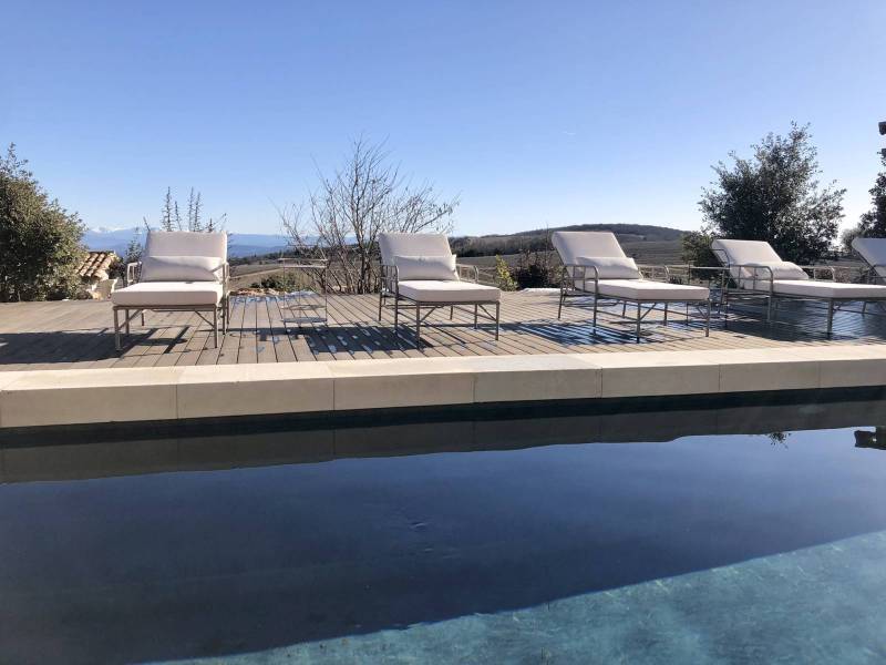 La piscine chauffée et sa plage en teck avec des chaises longues au Domaine Château du Bois