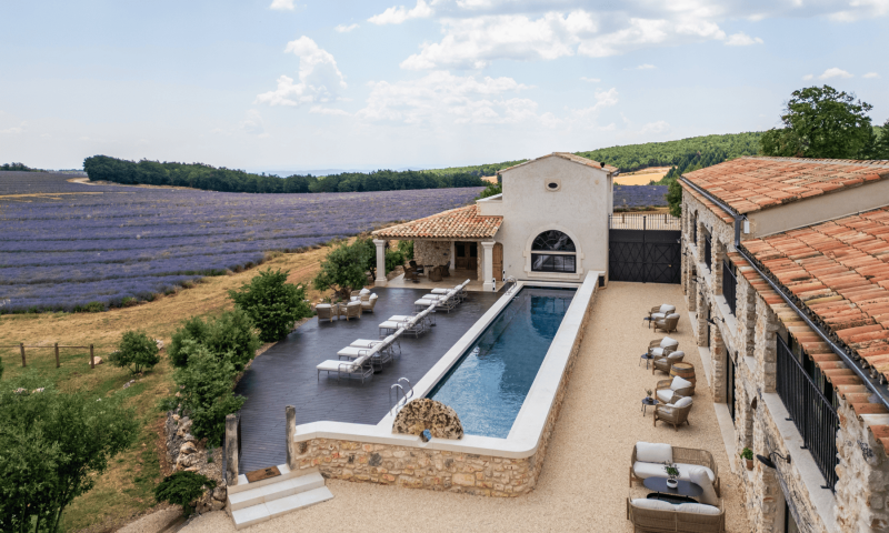 Vue d'ensemble du Domaine Château du Bois avec sa piscine chauffée, sa plage en bois et ses champs de lavande